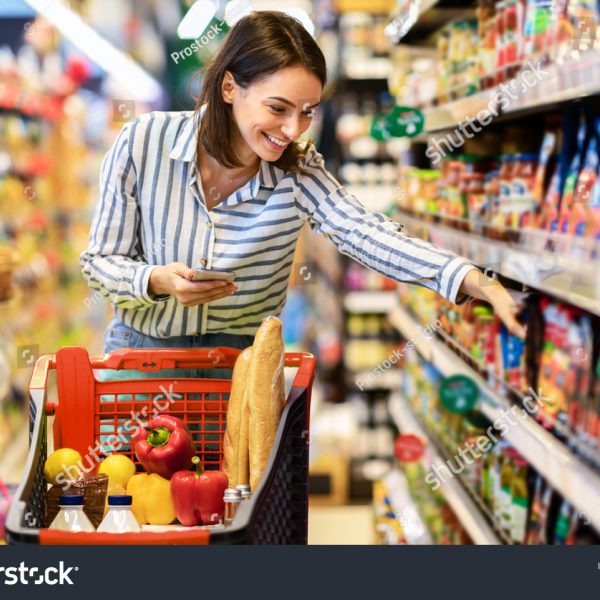 stock-photo-shopping-young-smiling-woman-holding-and-using-mobile-phone-buying-food-groceries-standing-in-1879822924